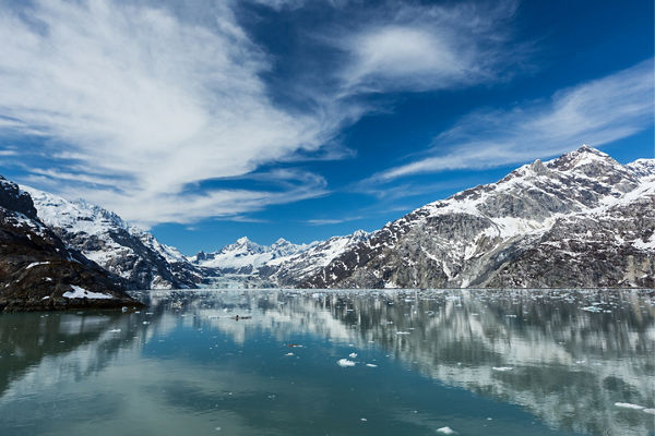 Snow-capped mountains reflected in icy blue lake