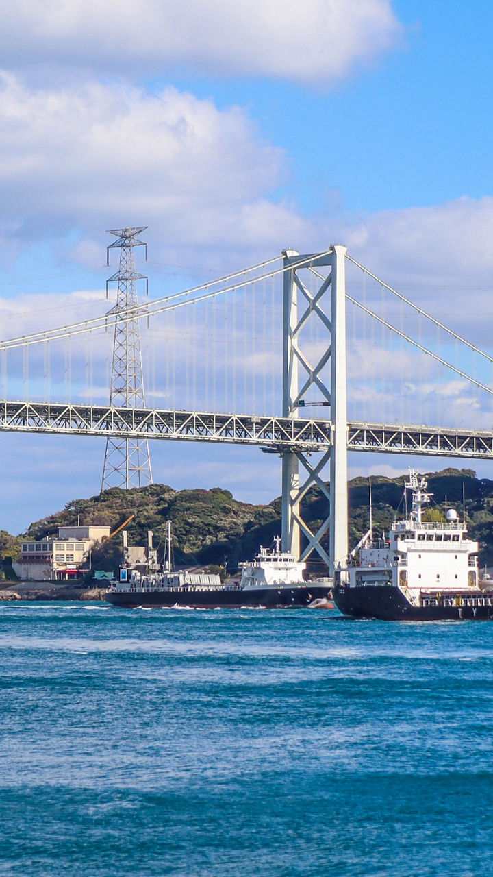 Cargo ship passing under large suspension bridge