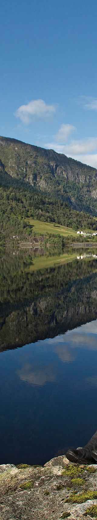 Woman sitting by serene mountain lake