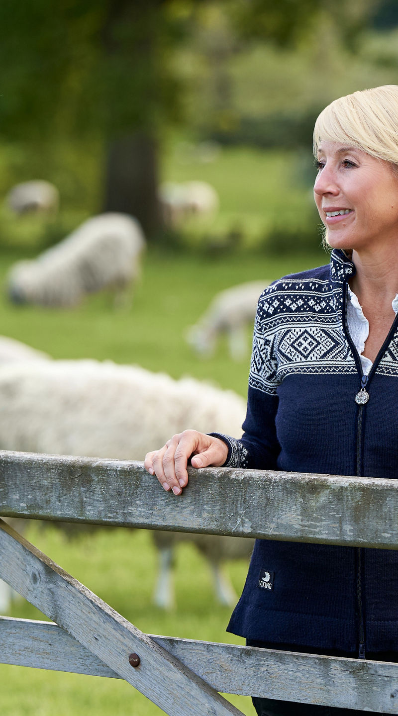 Woman in patterned sweater near sheep pasture