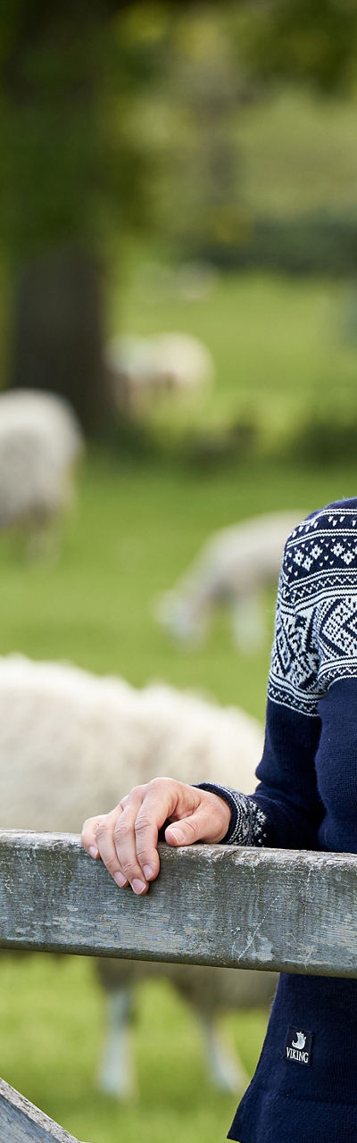 Woman in patterned sweater near sheep pasture