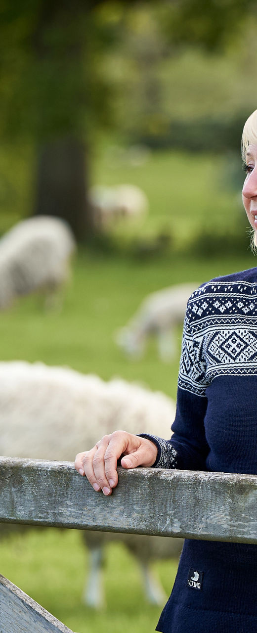 Woman in patterned sweater near sheep pasture