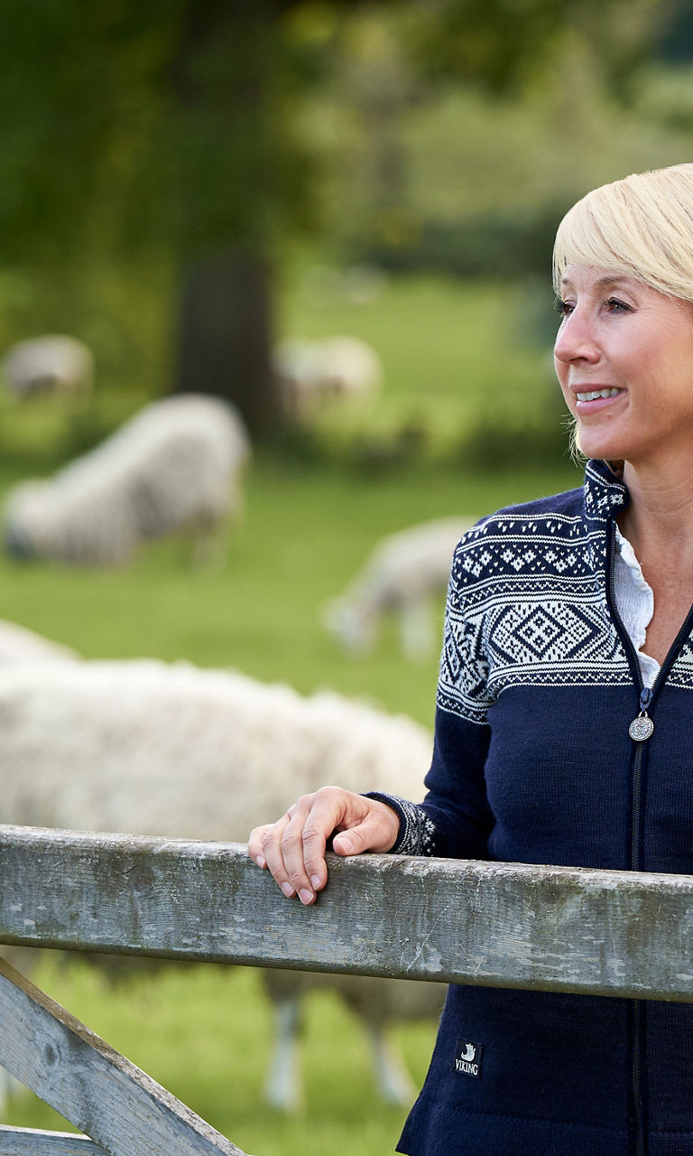 Woman in patterned sweater near sheep pasture
