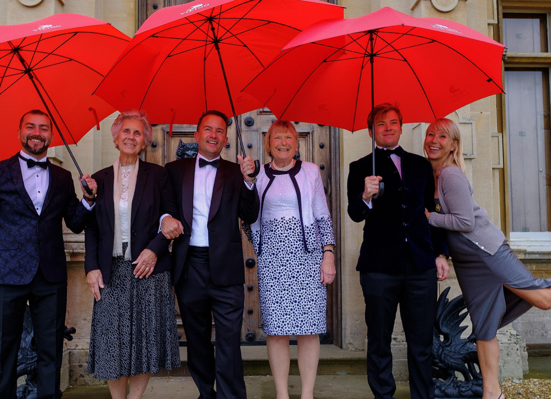 Group with red umbrellas at formal event
