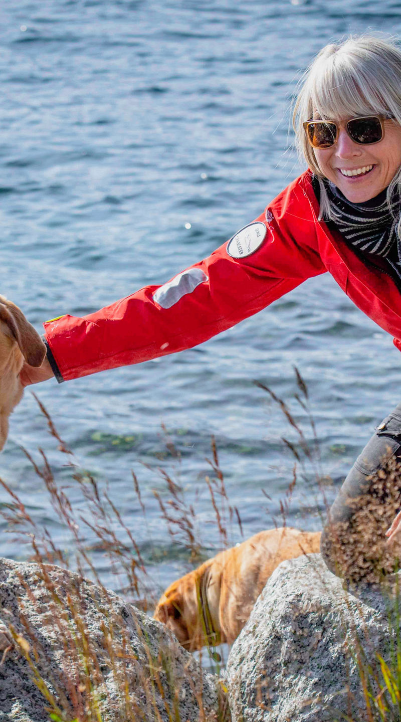 Woman in red jacket with dogs by lake