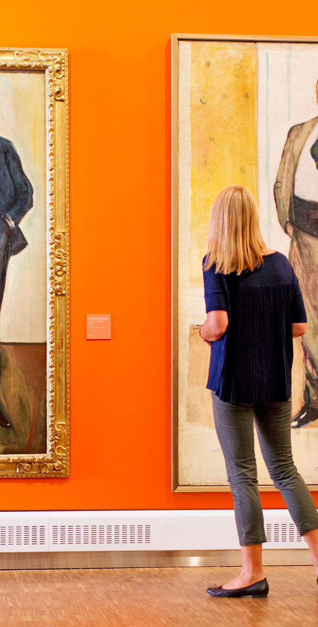 Woman admiring portraits in art gallery