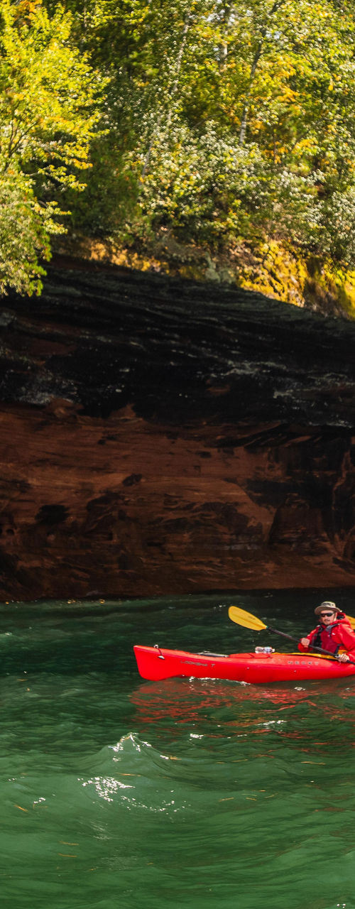 Red kayaks exploring rocky shoreline