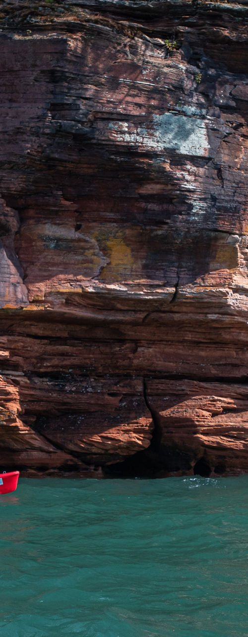 Kayakers explore rocky cliffside in calm waters