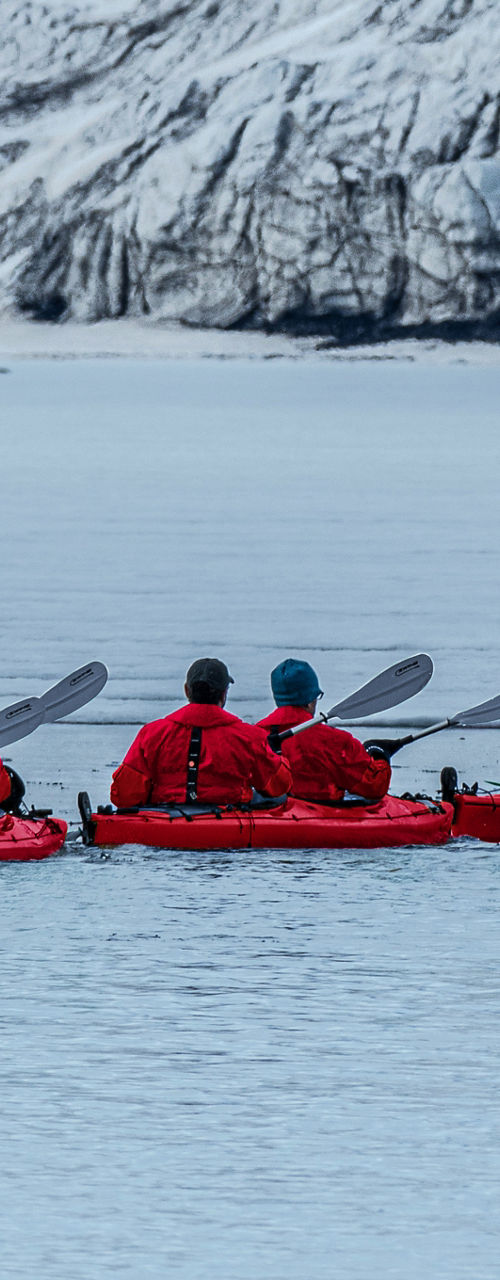 Group Kayaking Near Snowy Glacier Landscape