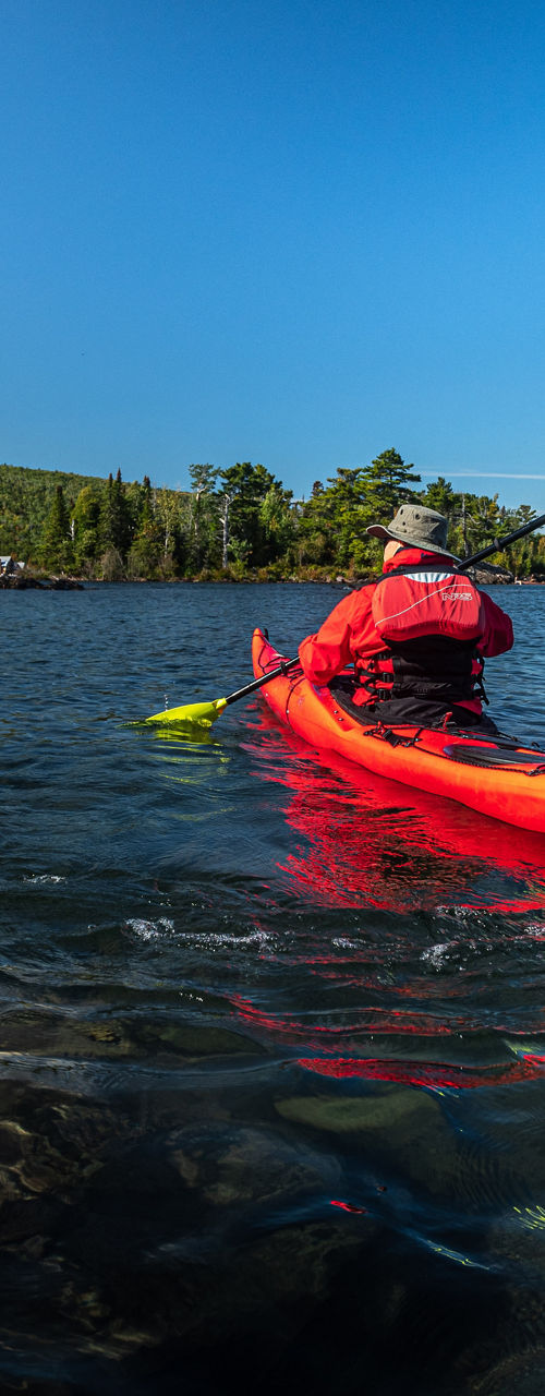 Red kayak on calm lake under blue sky