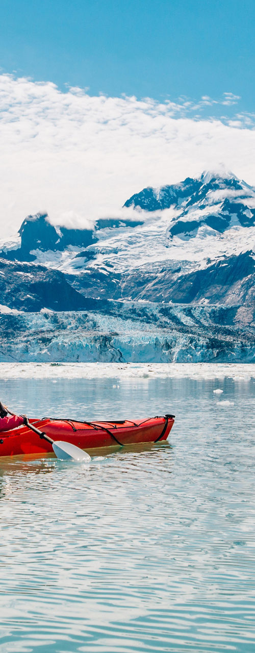 Solo Kayaker Paddling in Glacier Mountain Lake
