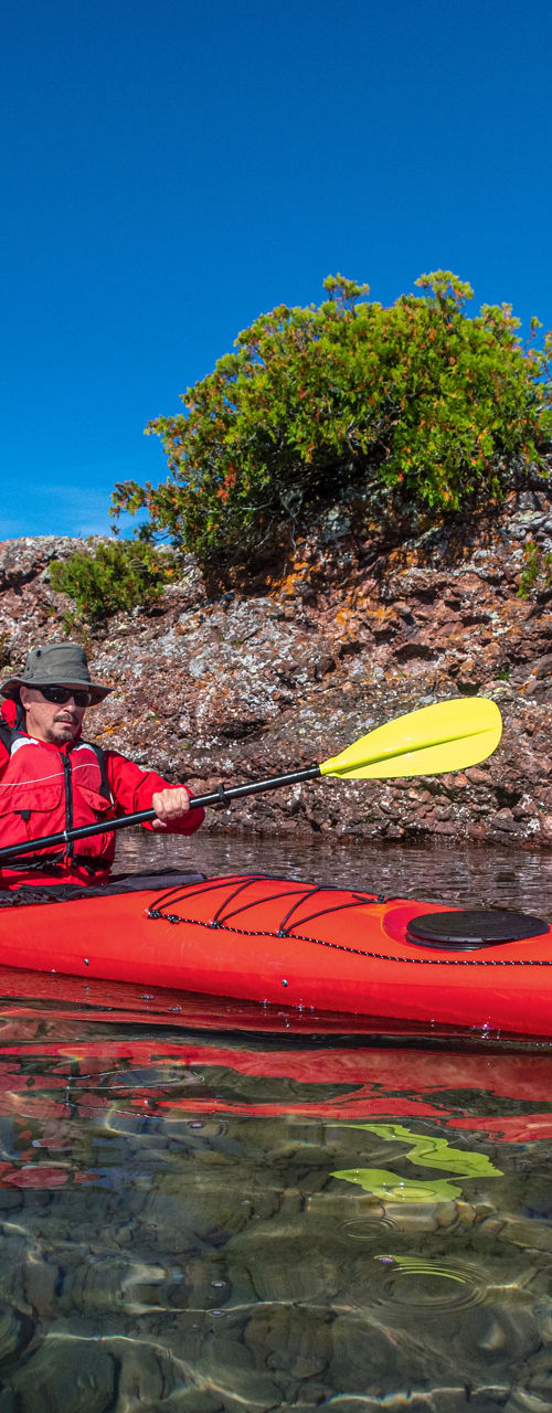 Red kayak on clear water near rocky shore