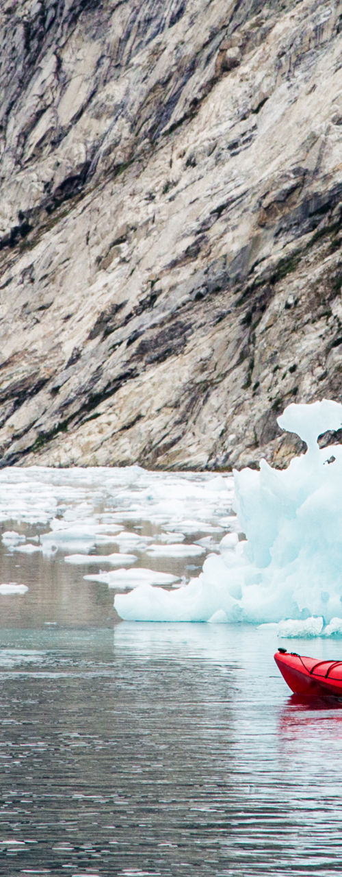 Kayakers exploring icy waters near glacier