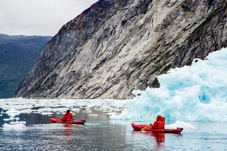 Kayakers exploring icy waters near glacier