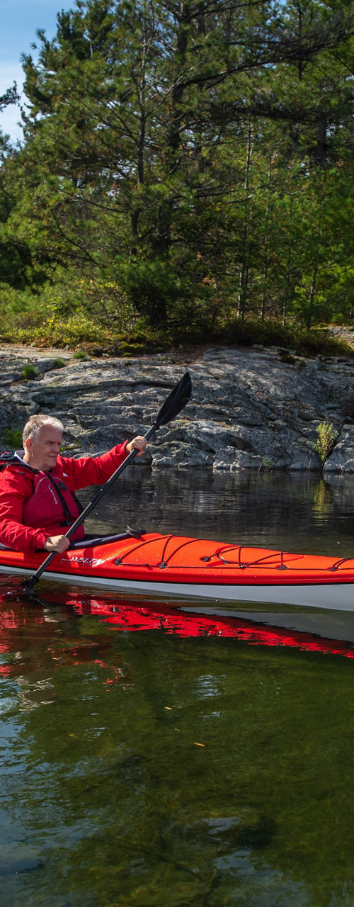 Two kayakers in red jackets on calm lake