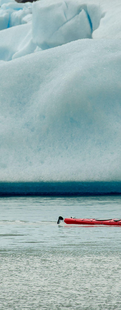 Kayakers near glacier in icy waters