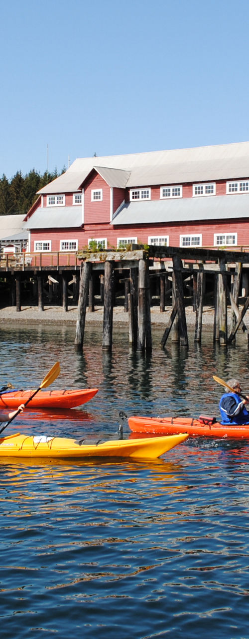 Kayakers near wooden pier and red building