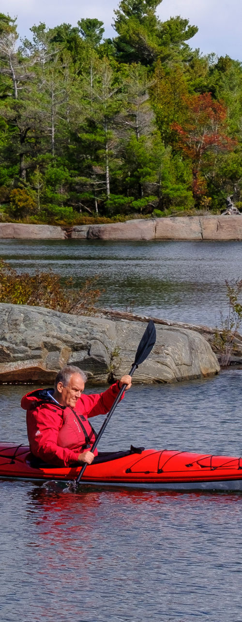 Two kayakers in red gear on scenic lake