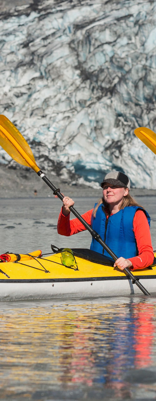Two kayakers near glacier in calm waters