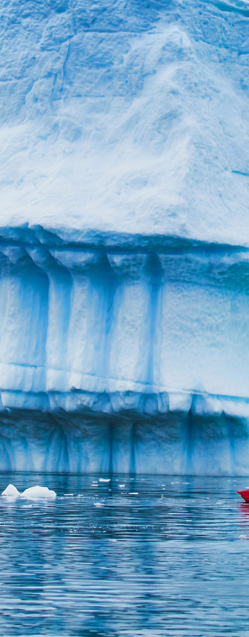 Red kayak near massive blue iceberg