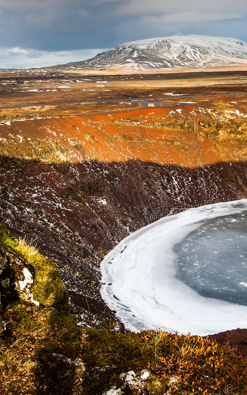 Frozen crater lake in rugged landscape