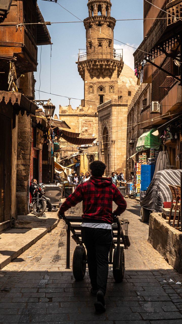 Man pushing cart through historic Middle Eastern street