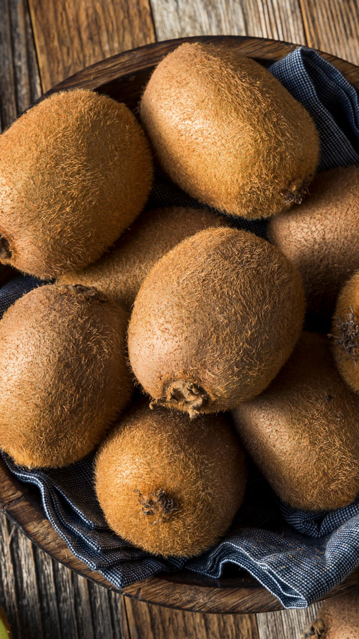 Fresh whole and sliced kiwis on wooden table
