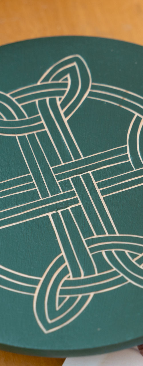 Green Celtic knot coaster on wooden table