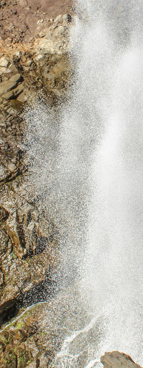 Tourists watch ocean geyser at rocky cliff