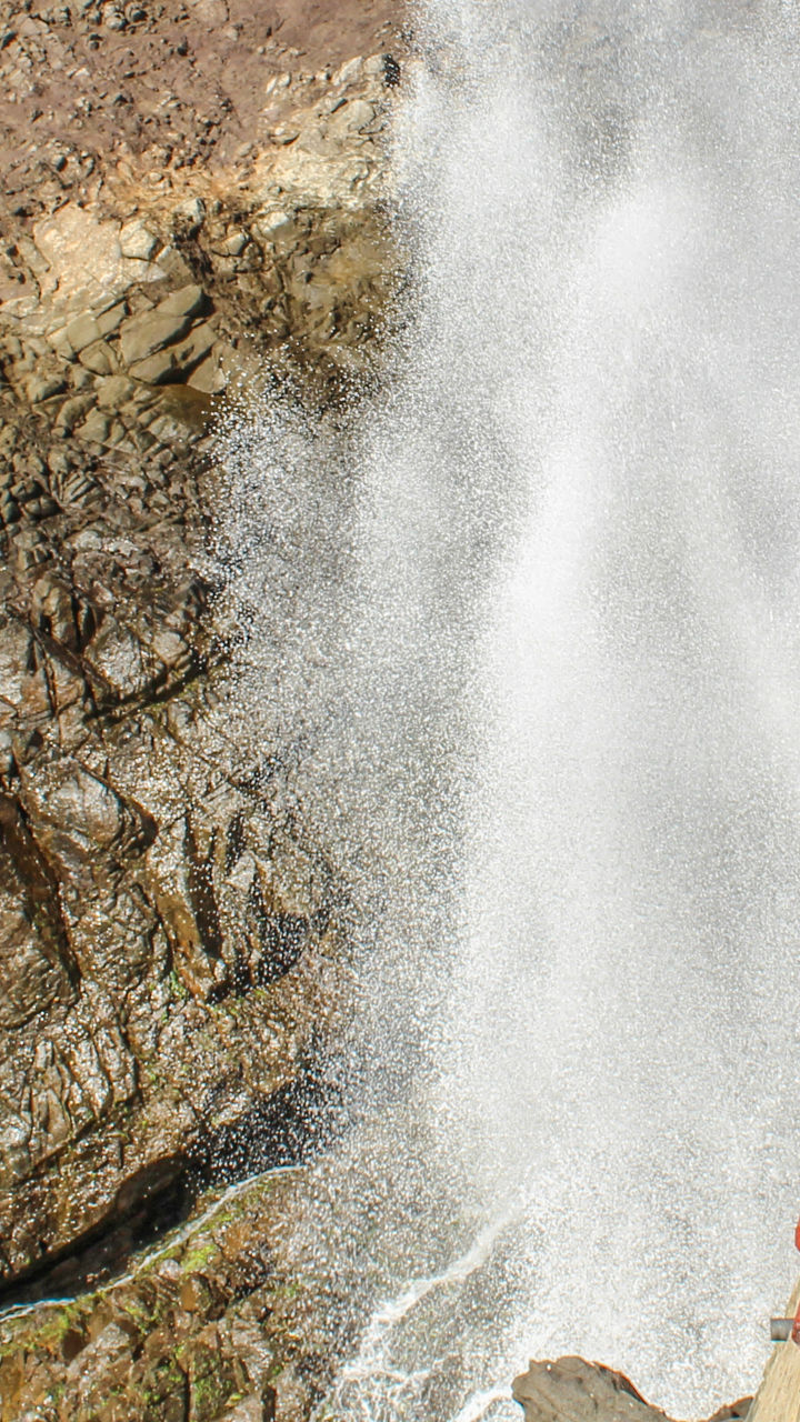 Tourists watch ocean geyser at rocky cliff