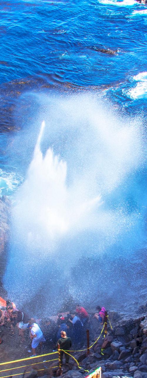 Coastal blowhole with tourists watching spray