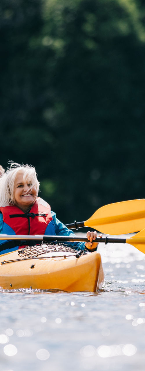 Two people kayaking on a calm forest lake