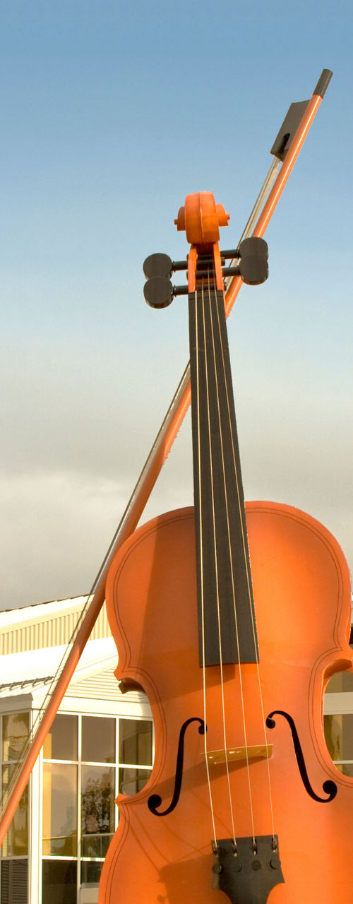 Large violin sculpture outside modern building