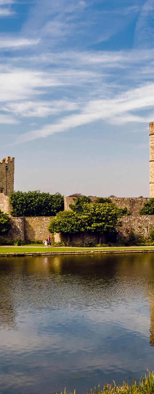 Historic castle by serene lake under blue sky