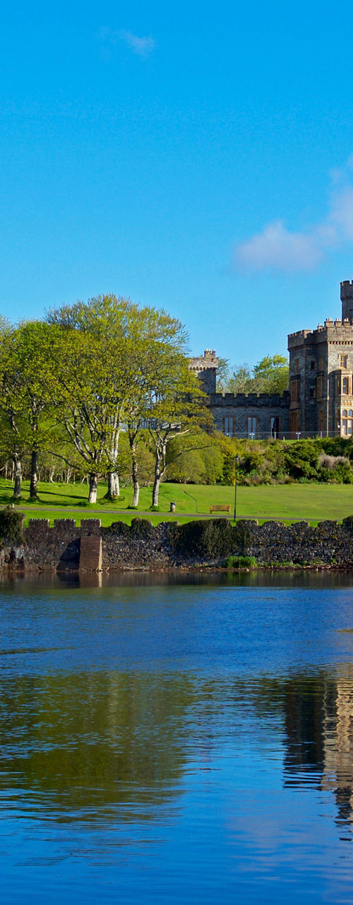 Historic castle by serene lake under blue sky