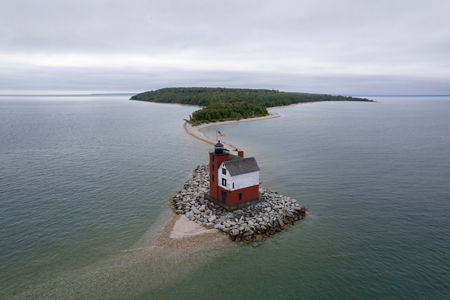 Red lighthouse on rocky island in calm lake