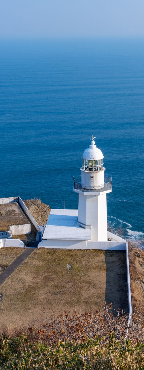 White lighthouse on coastal cliff overlooking ocean