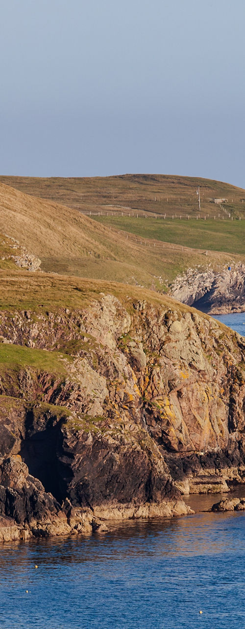 Coastal cliffs with lighthouse in distance