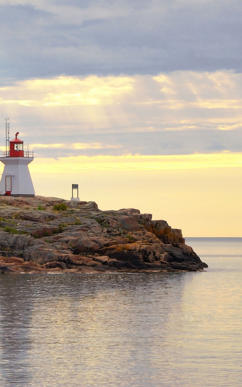 Scenic lighthouse on rocky coastline at sunset