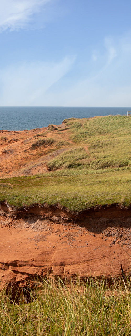 Coastal lighthouse on red cliffs under blue sky