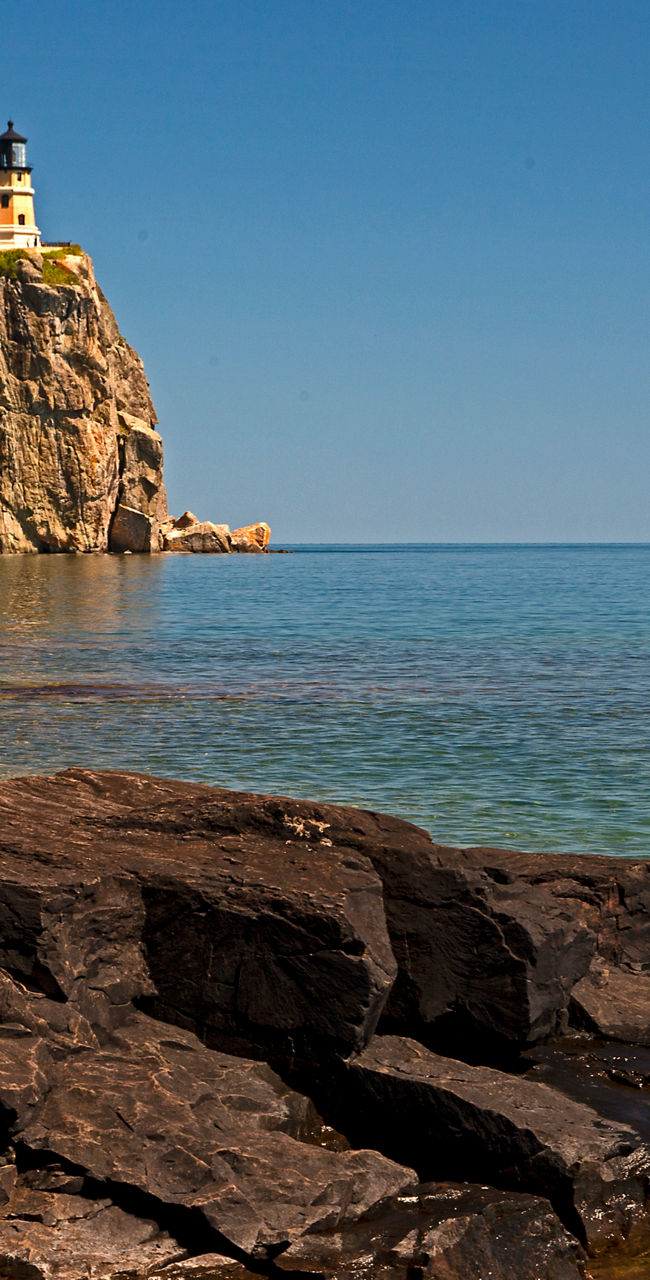 Scenic lighthouse on rocky cliff by lake