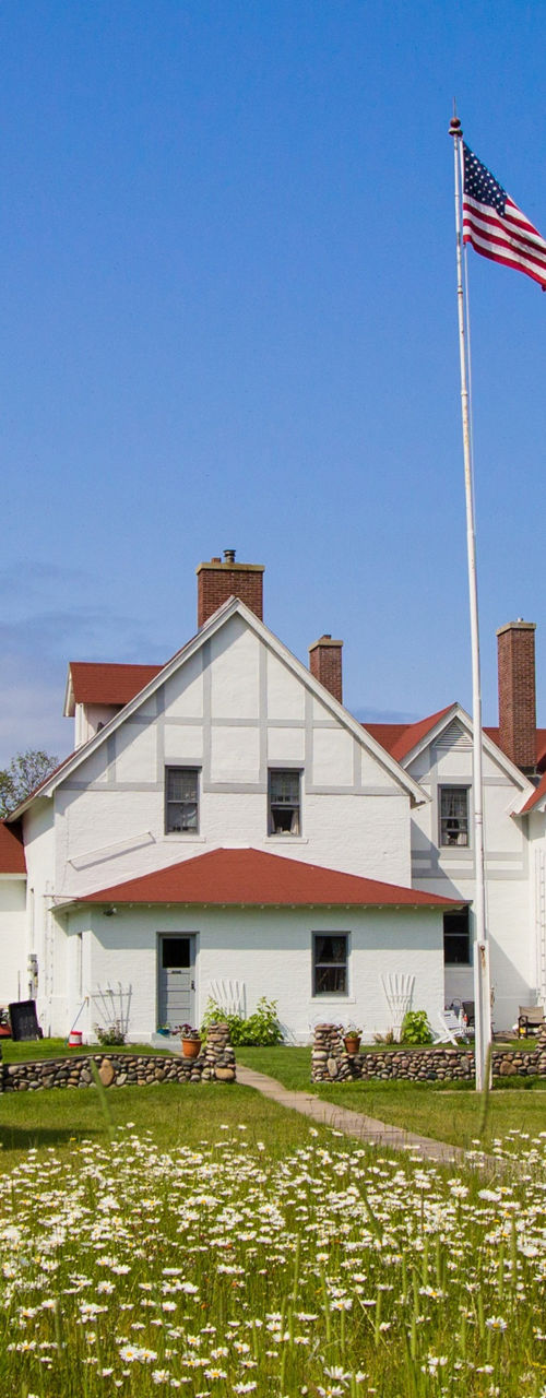 Historic lighthouse with American flag and garden
