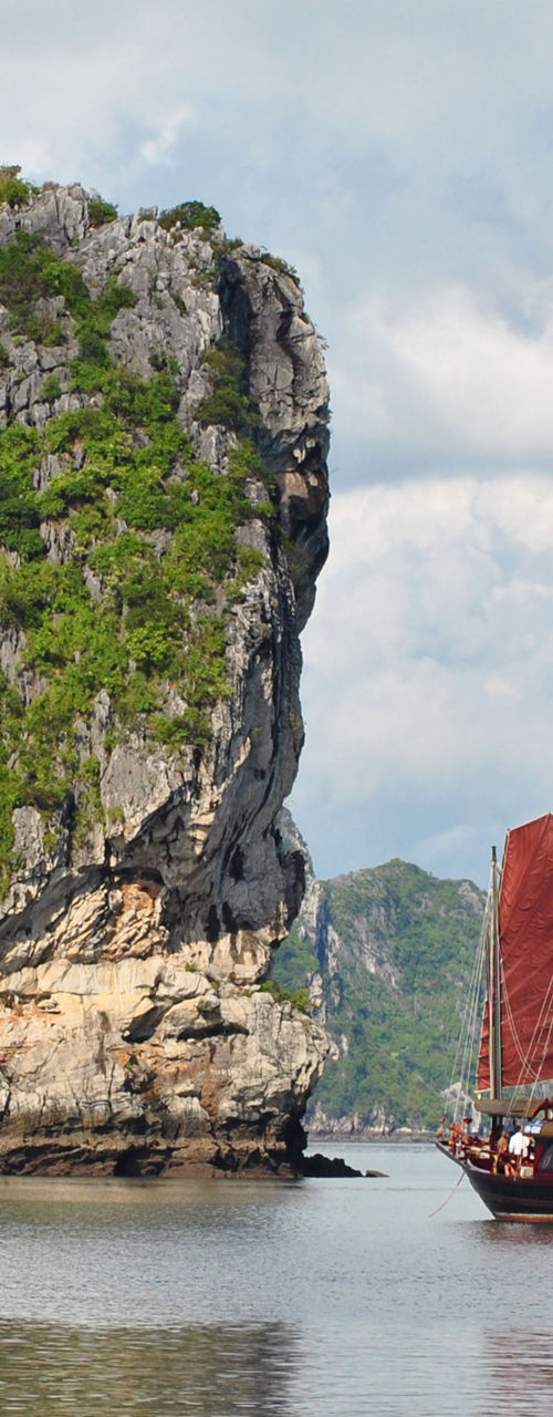 Traditional red-sailed boat in scenic bay