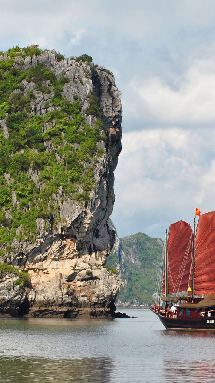 Traditional red-sailed boat in scenic bay