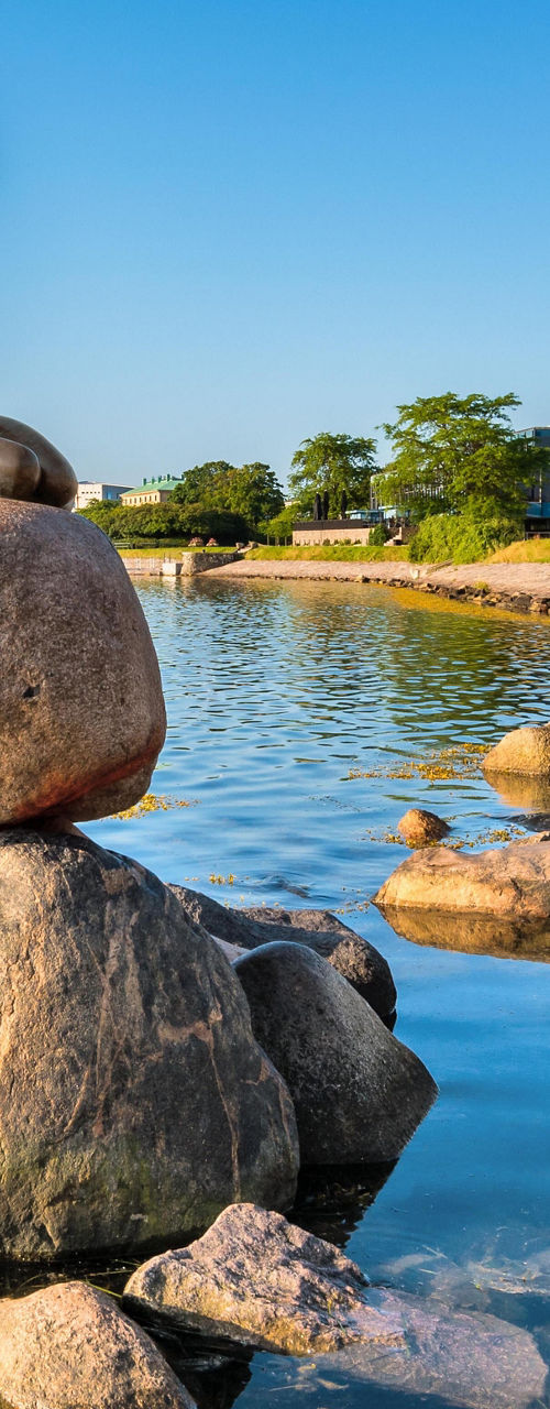 Little Mermaid statue by waterfront rocks