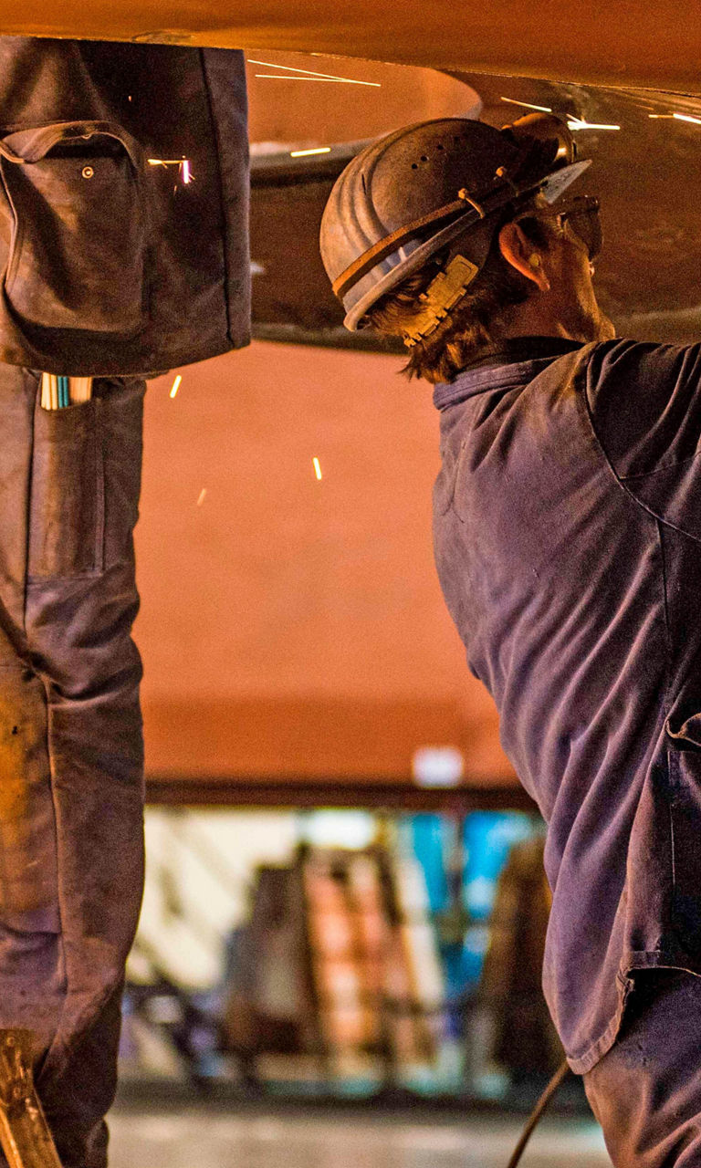 Industrial workers welding metal in workshop