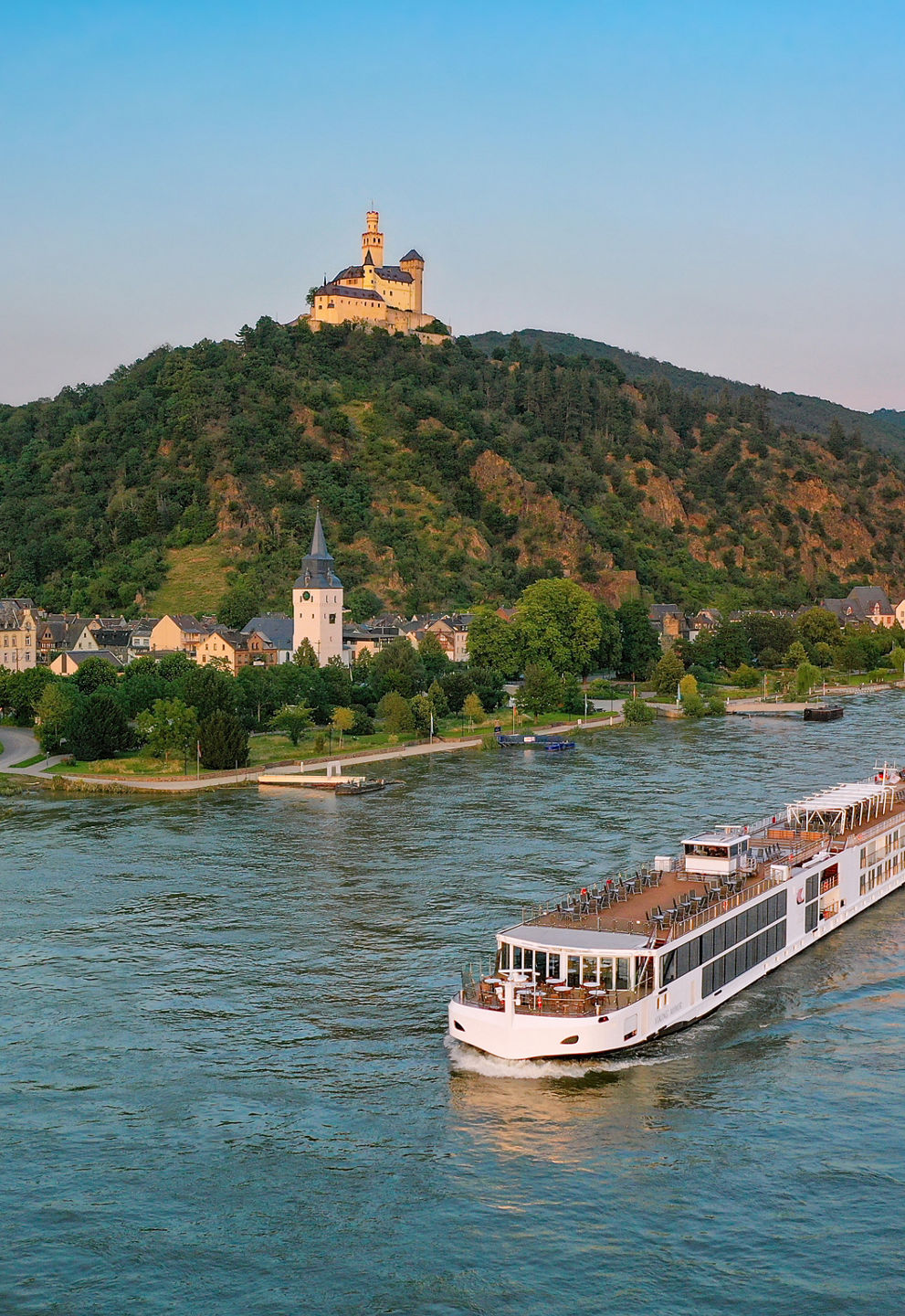 River cruise ship passing hillside castle town