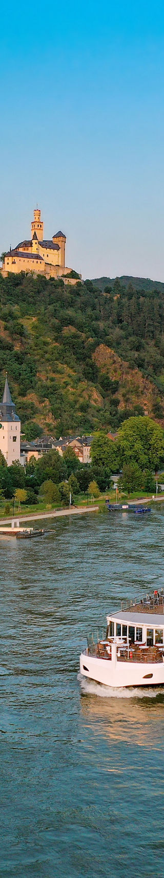 River cruise ship passing hillside castle town