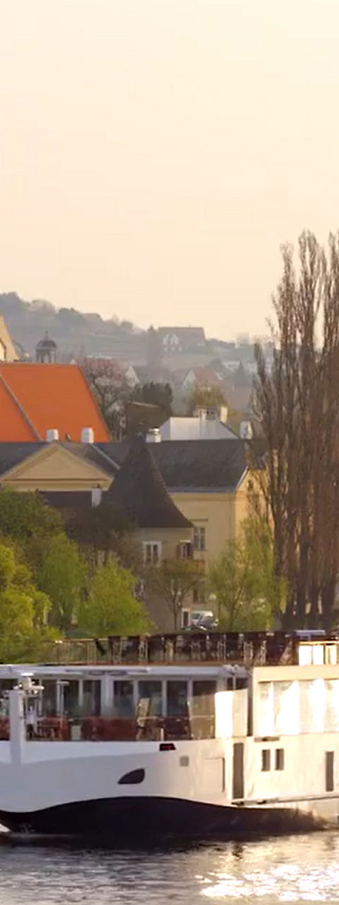 River cruise ship passing European town at sunset
