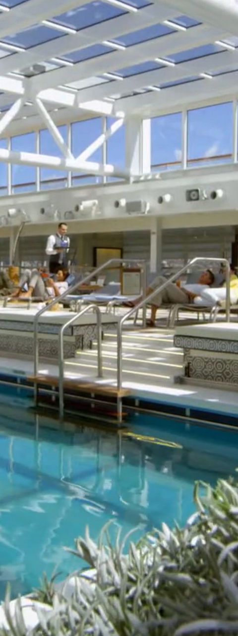 Indoor pool area with people relaxing on loungers